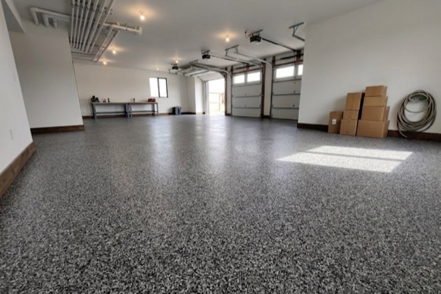 A three-bay garage with a grey and black flake floor running wall to wall under the overhead doors.